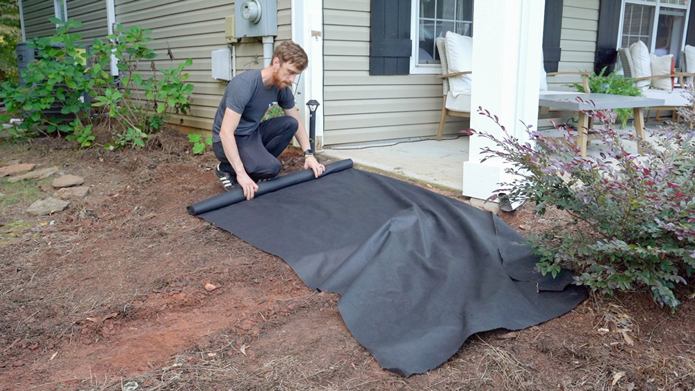 Man rolling out a tarp.