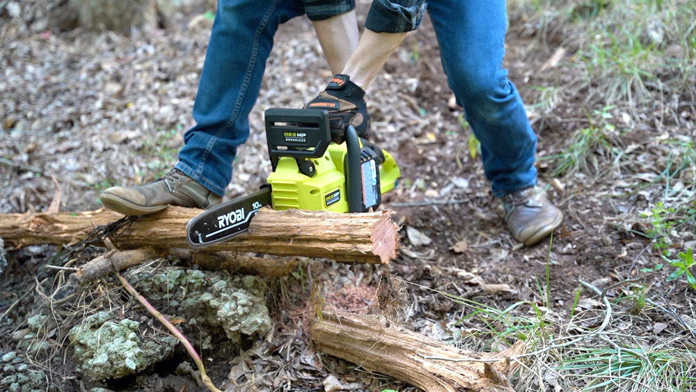 Person cutting firewood using a chain saw. Person cutting firewood using a chain saw.