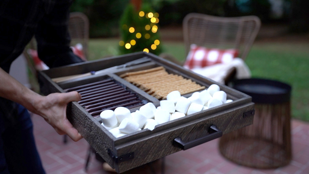 Man holding a tray of s’mores ingredients. Man holding a tray of s’mores ingredients.
