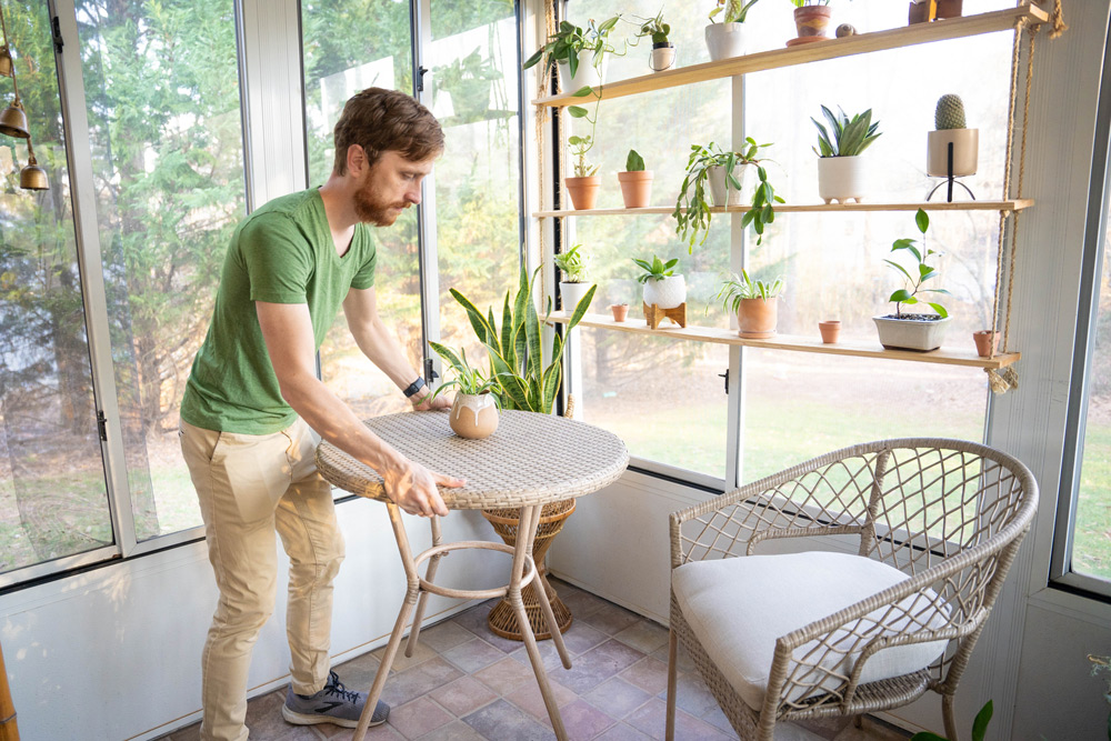 A person moving a small table with a plant on it. A person moving a small table with a plant on it.