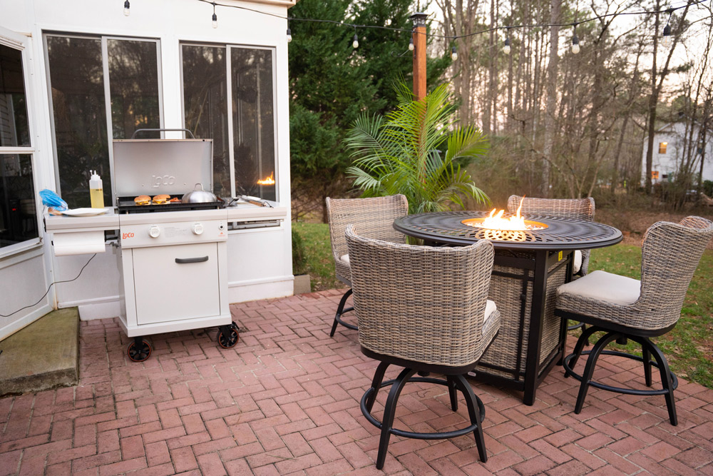 A back patio with a grill and a table fire pit with four chairs. A back patio with a grill and a table fire pit with four chairs.