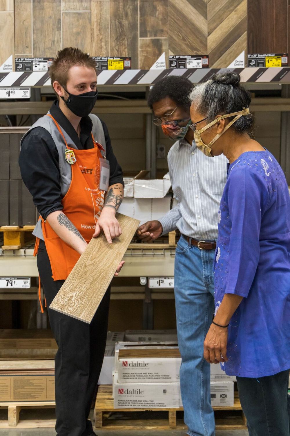 Home Depot Associate showing a man and a woman a wooden board