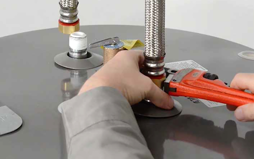 A man tightening pipe on water heater for faucet reconnection A man tightening pipe on water heater for faucet reconnection