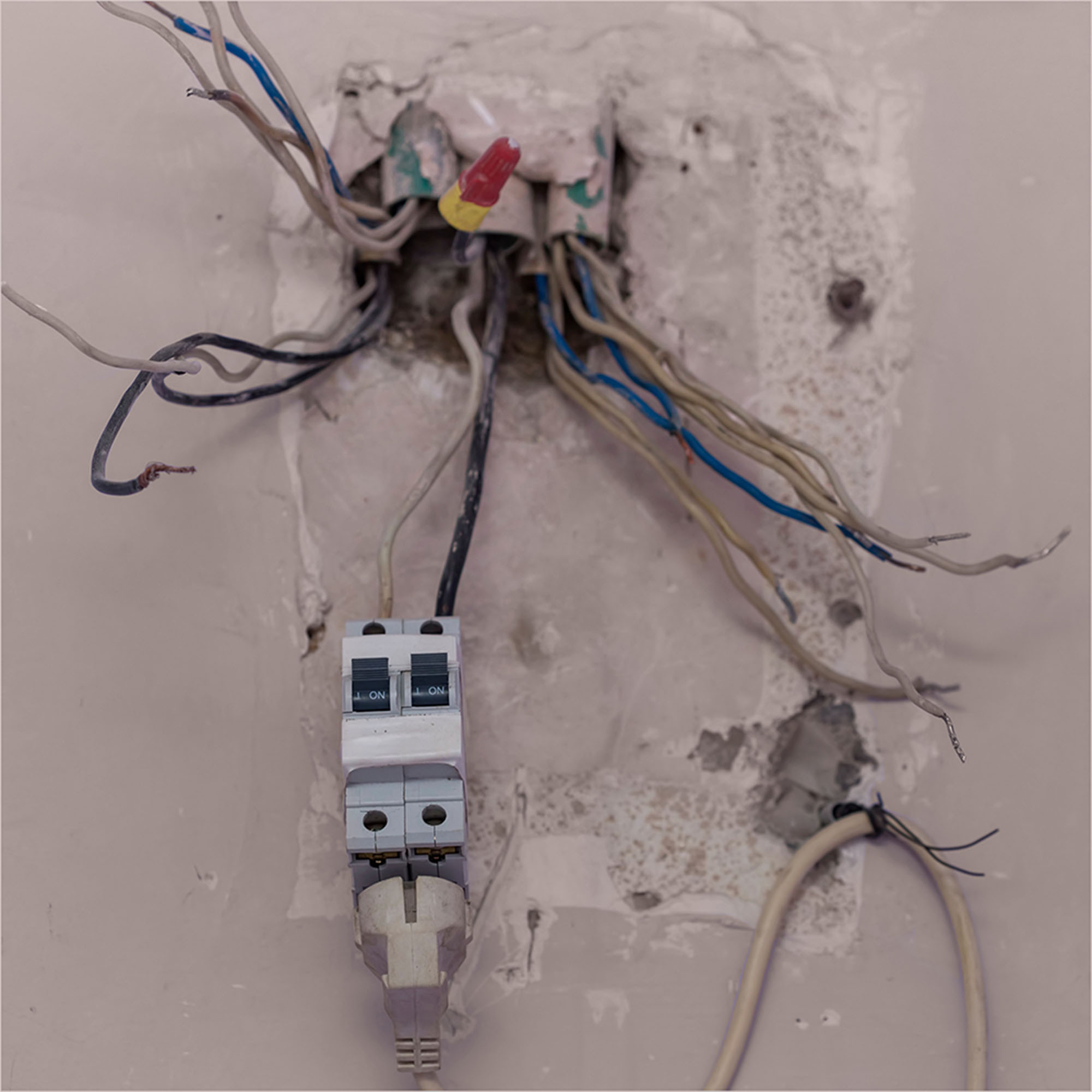 Old wiring hangs from a wall outlet.