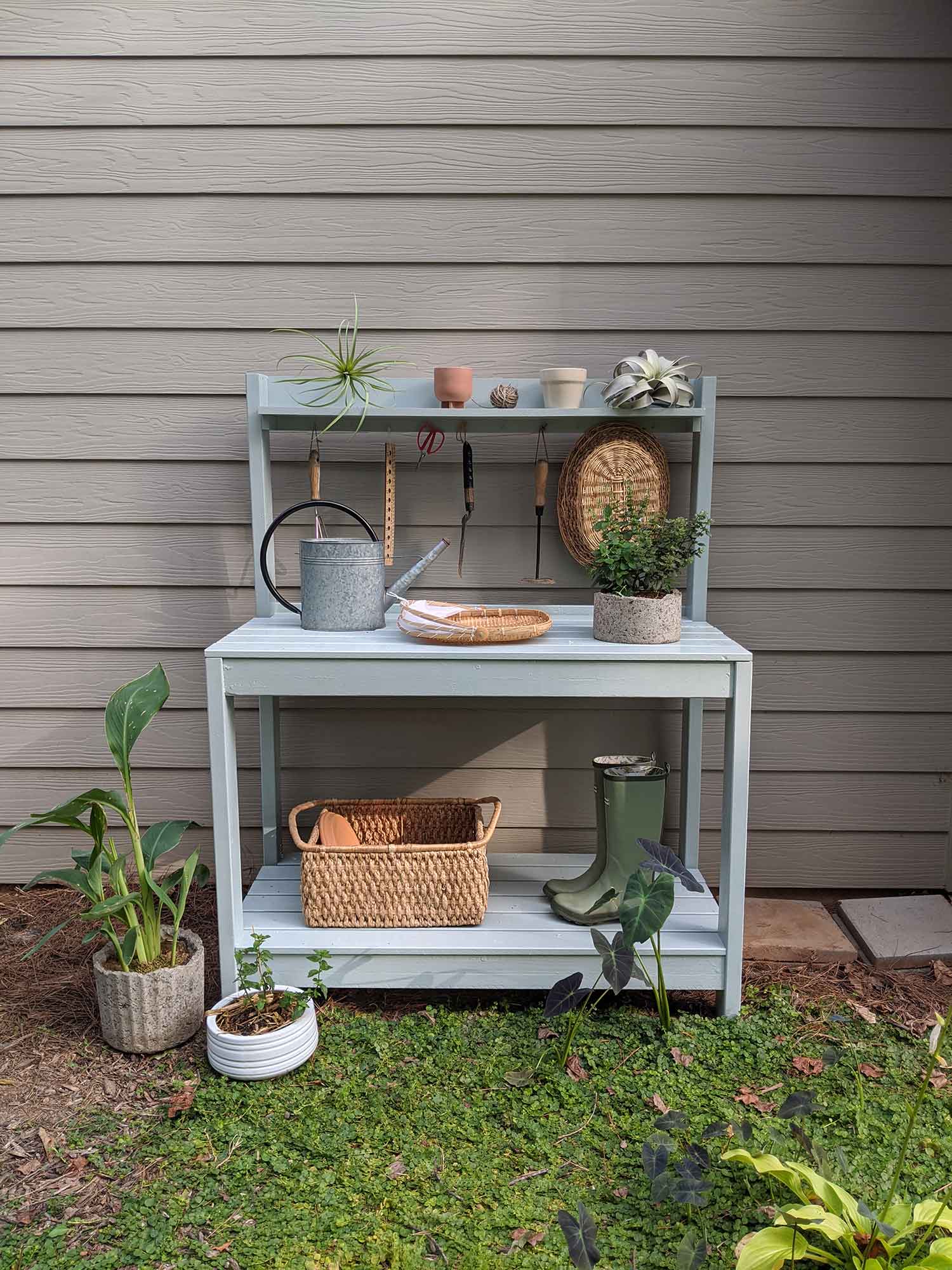 Finished potting table with plants, baskets, and watering can on top
