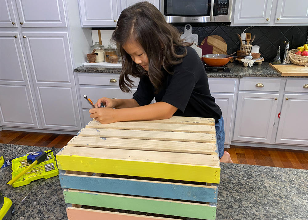 Child marking on the crate with a pencil.