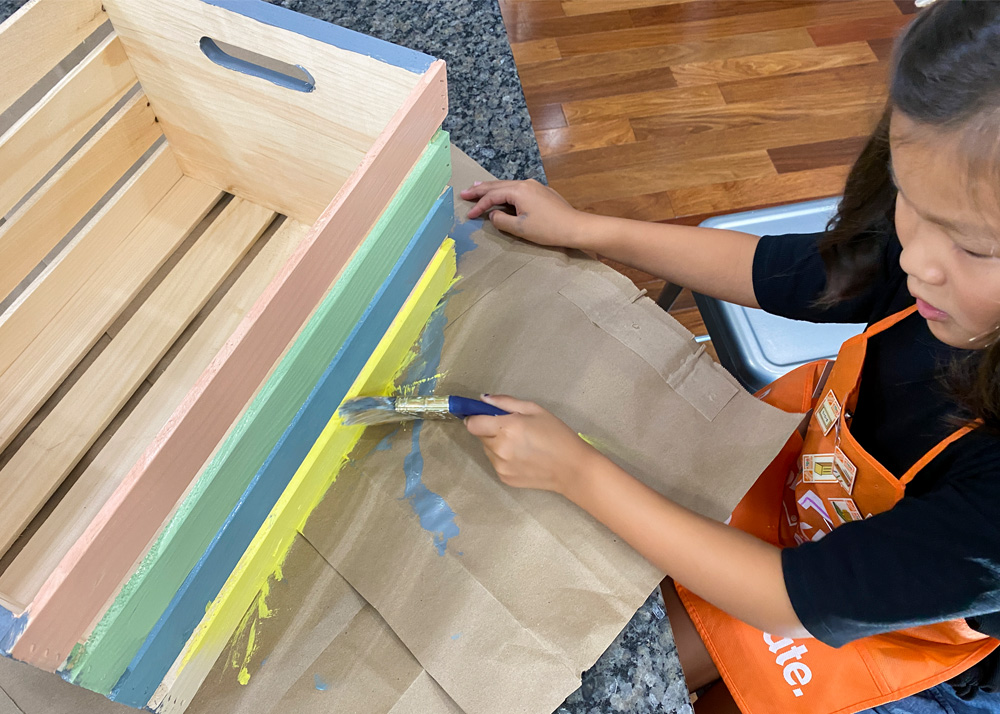 Child painting her wooden crate.