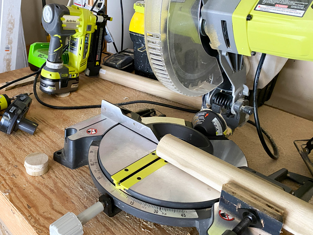 A miter saw with a round dowel ready to be cut.