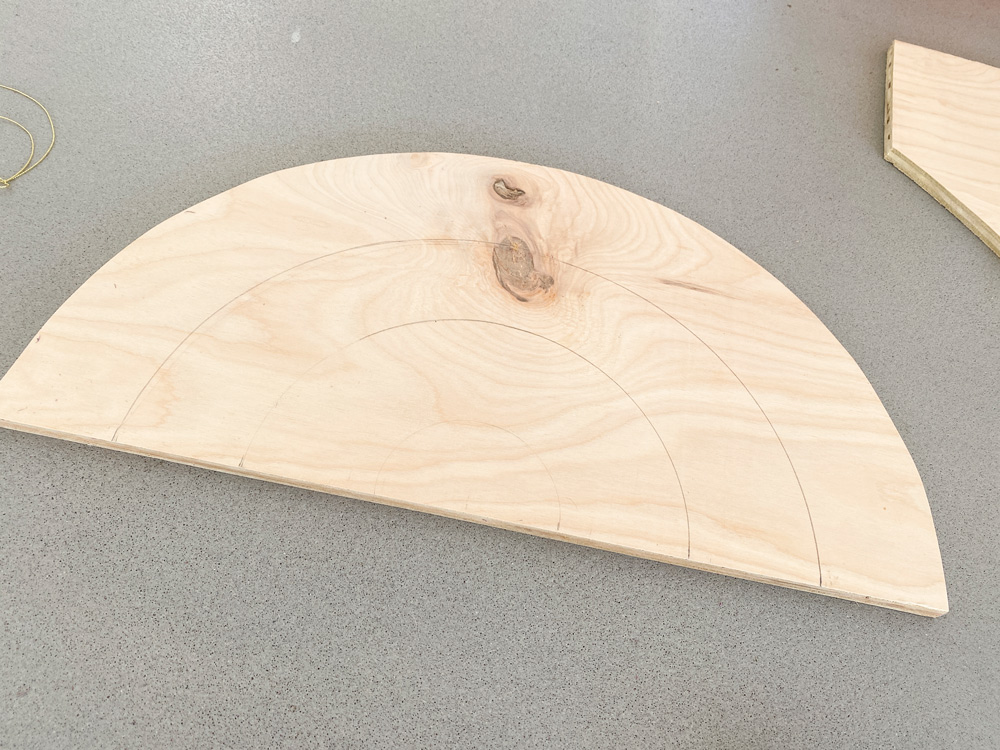 A half-moon–shaped piece of plywood with two half moons sketched.
