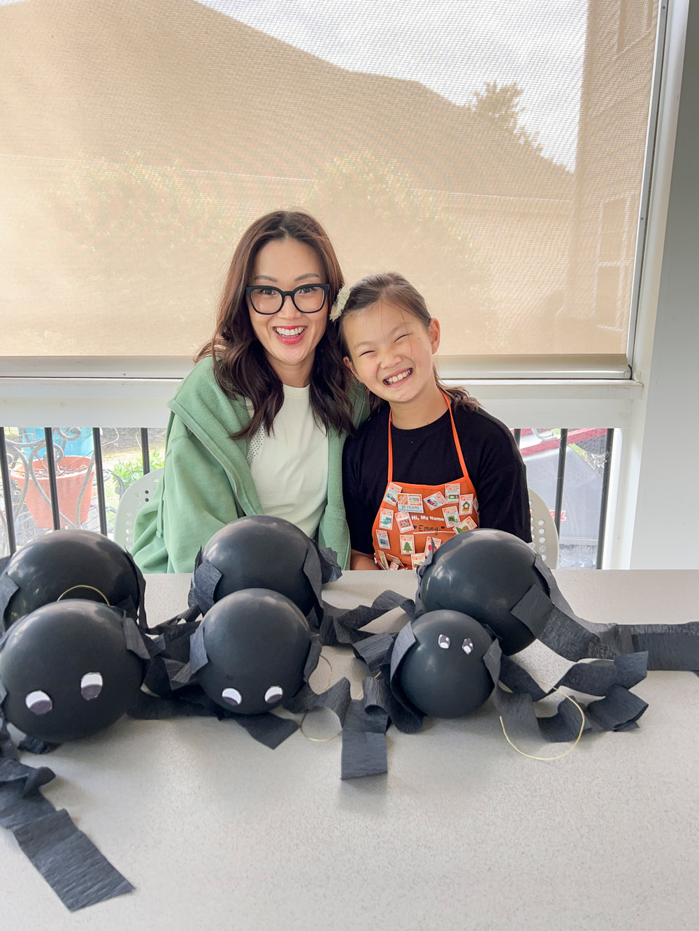Two people smiling in front of DIY balloon spiders.