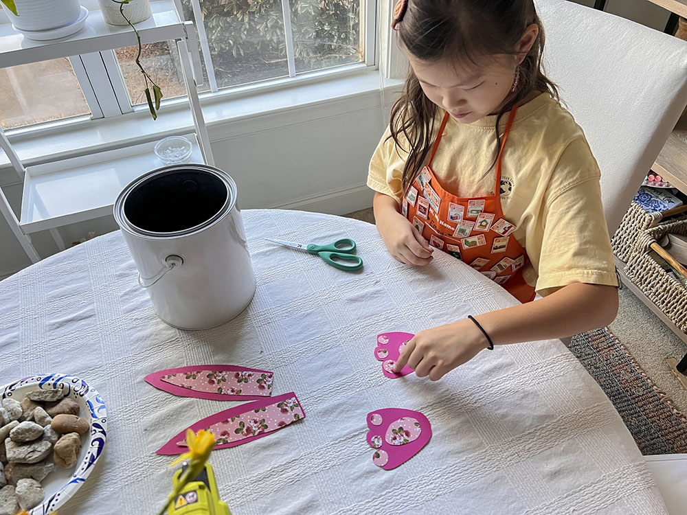 Girl placing patterned pieces of paper on top of paper cut outs.