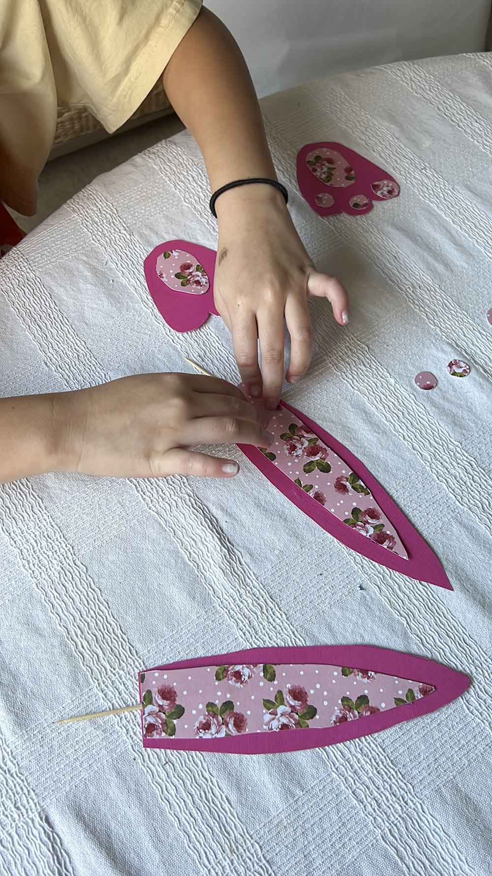 Girl placing piece of patterned paper down on larger piece of pink paper.