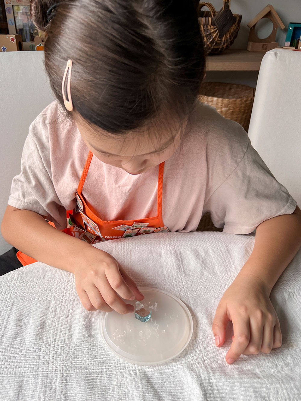 Girl gluing fire glass on container lid.