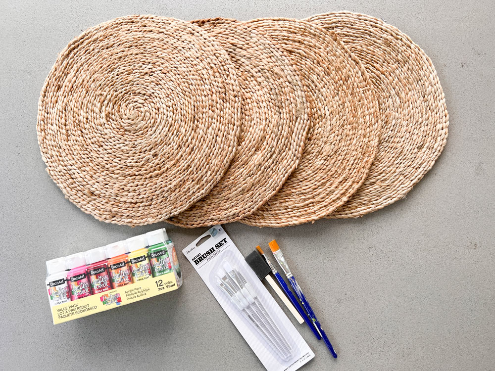 Placemats, paint and brushes spread out on a surface.