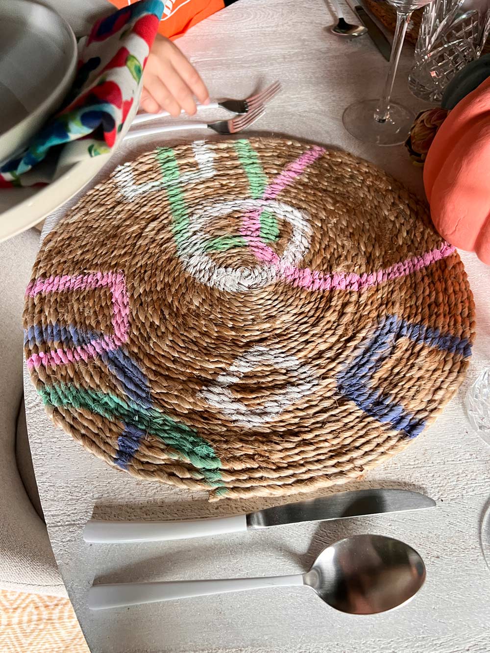 A person setting the table with the painted placemats.