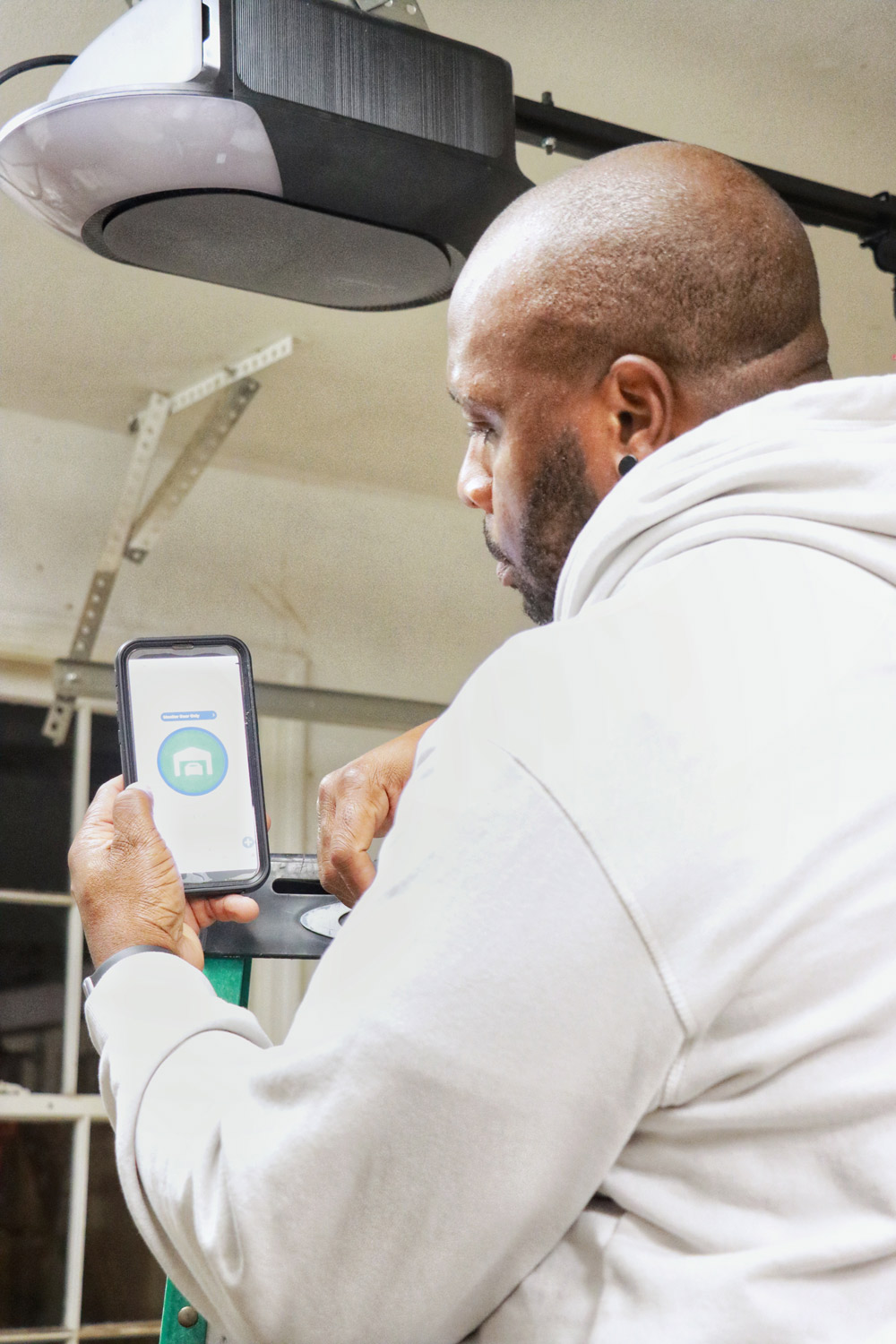 Man using MyQ mobile app to synch with his garage door opener.
