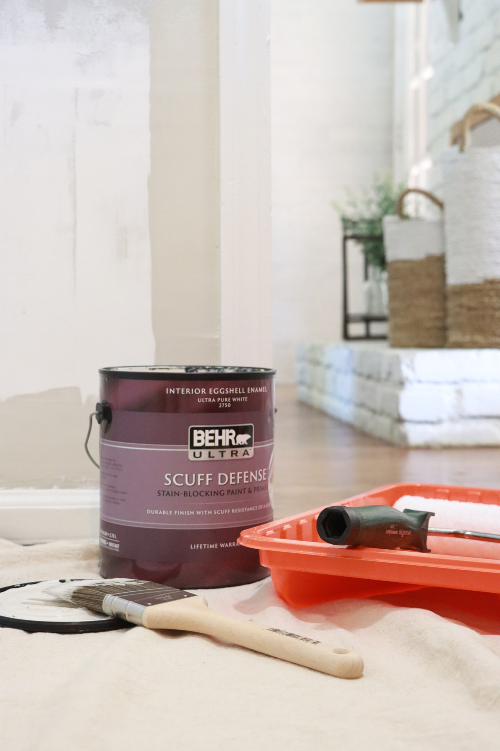 A product picture of Behr ultra scuff defense paint surrounded by paint supplies.