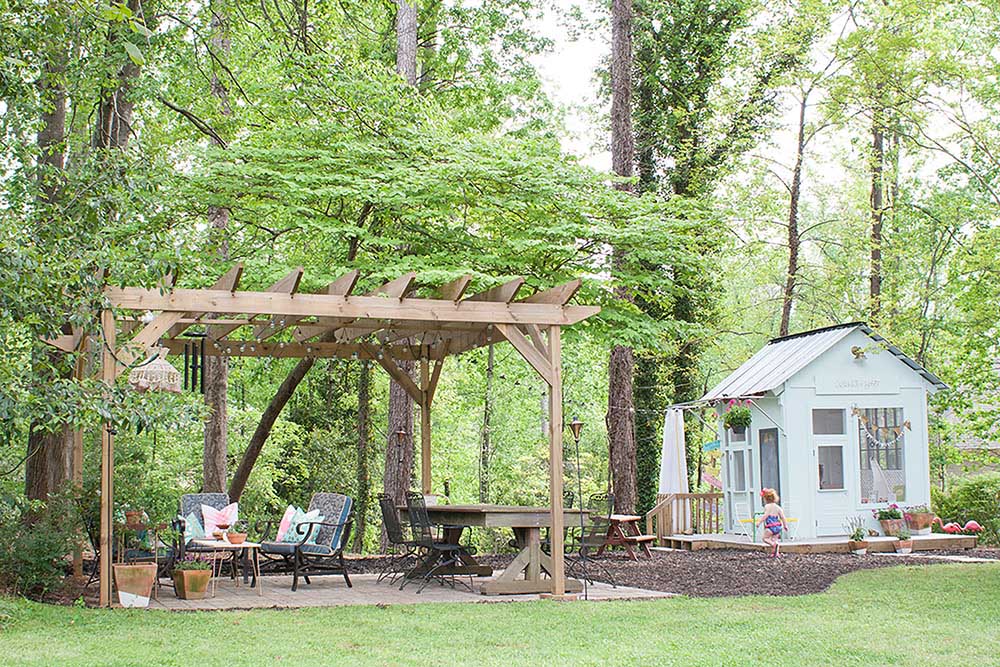 A backyard landscaped with mulch around a kid's playhouse.