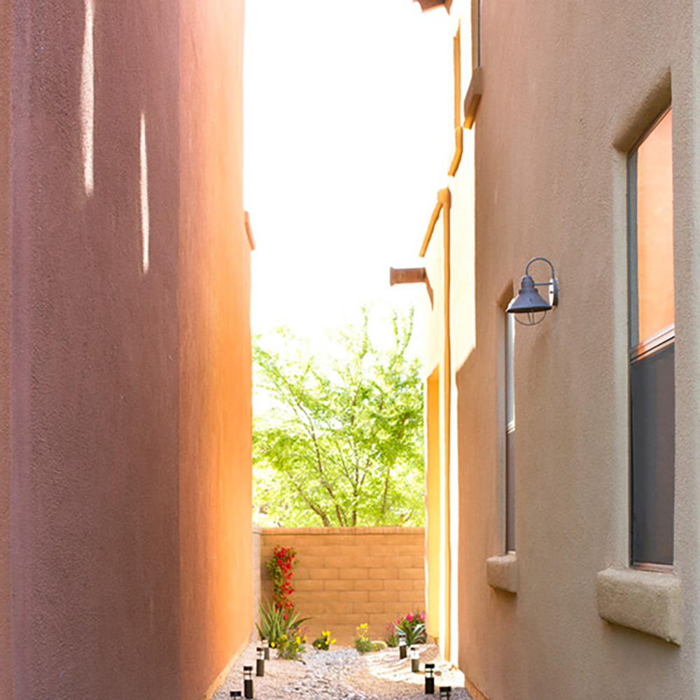 A DIY yard drainage solution on the side of a home decorated with landscape lighting.