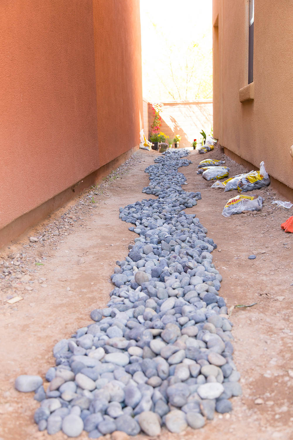 A pathway of Mexican beach pebbles between two outside walls.