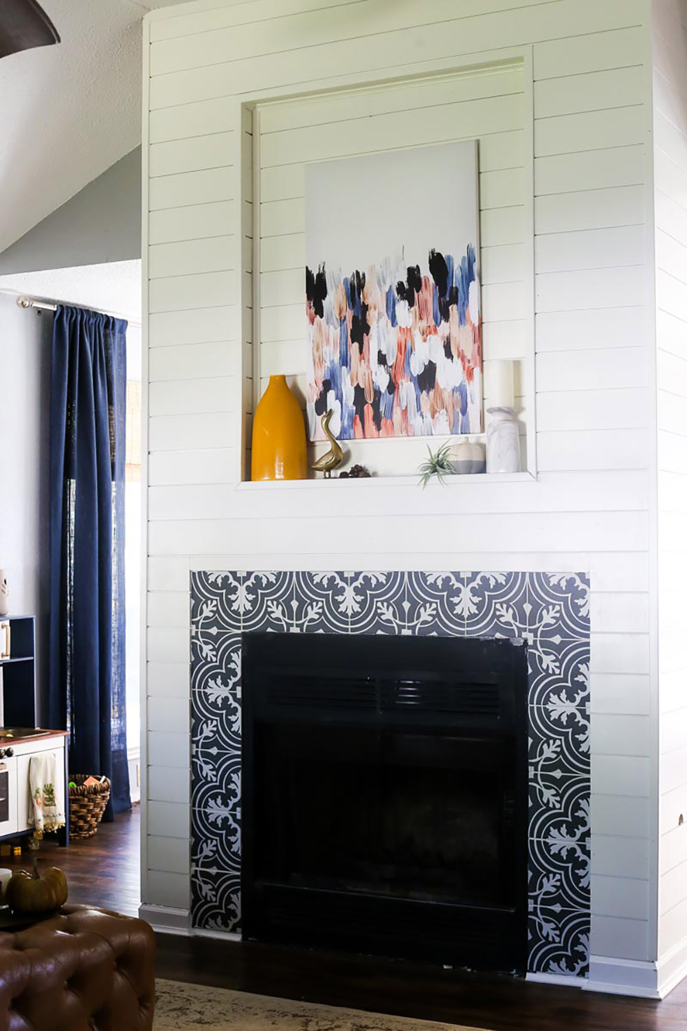 A fireplace with mosaic tile, shiplap and wall art.
