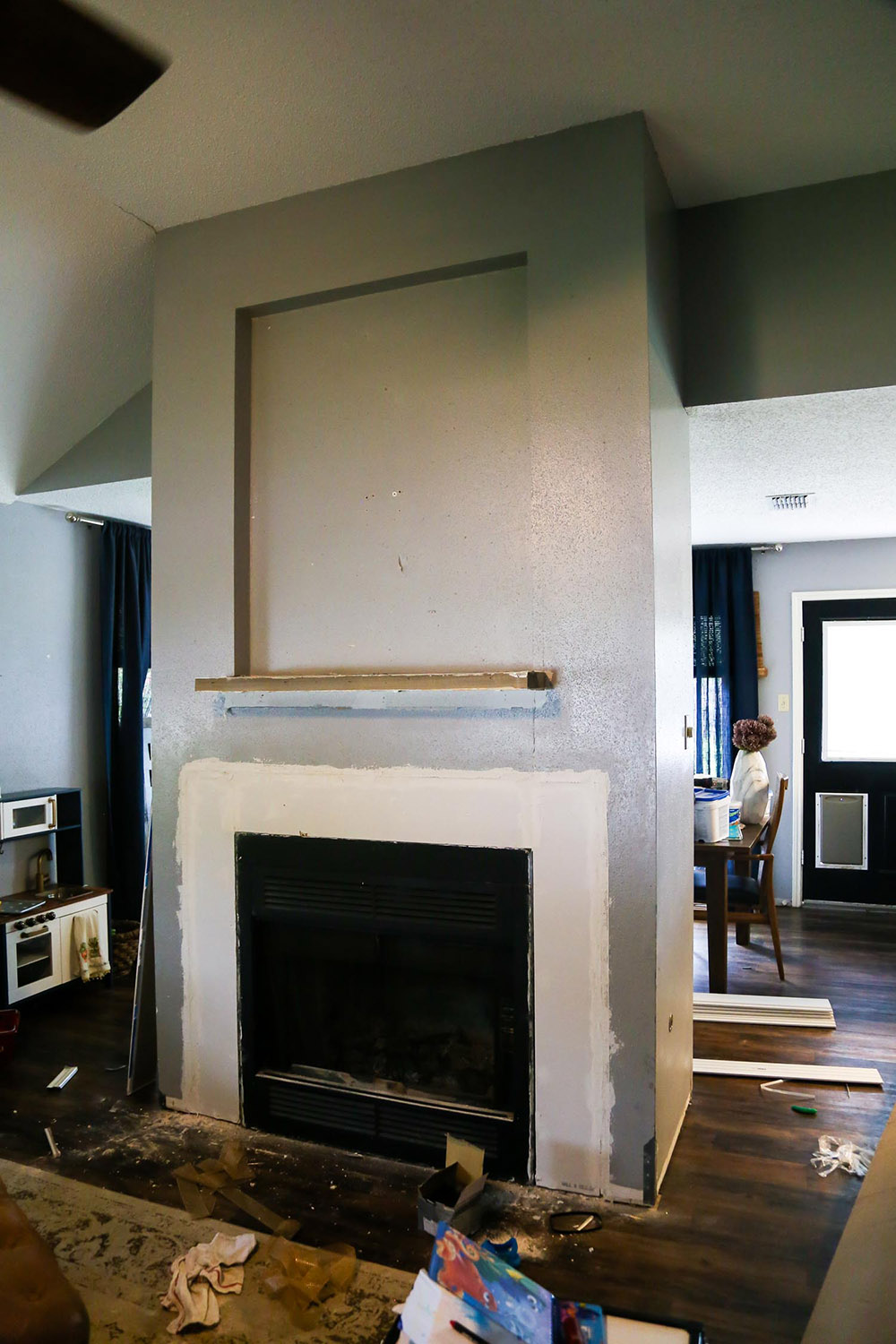 A grey and white fireplace in a living room space.
