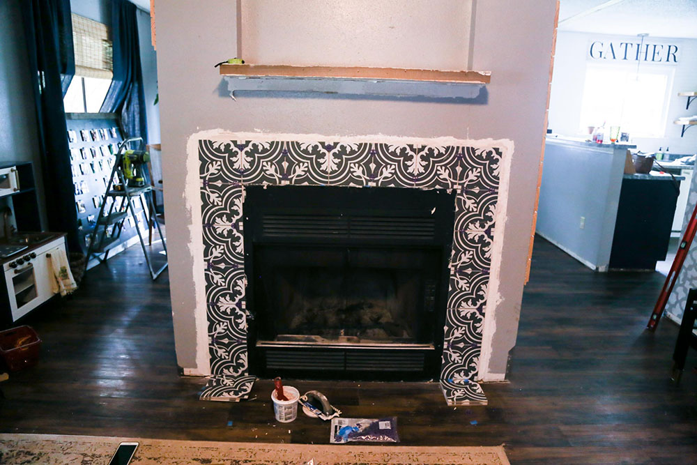 A fireplace under renovation with plaster being applied to the tiles.