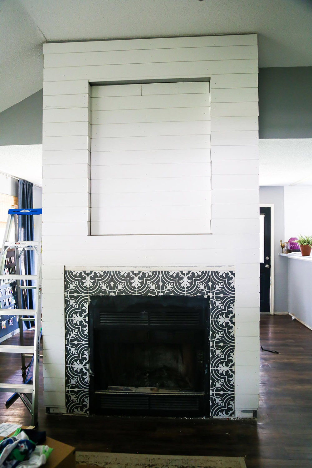 A fireplace with white shiplap exterior and mosaic tiles around the fireplace.