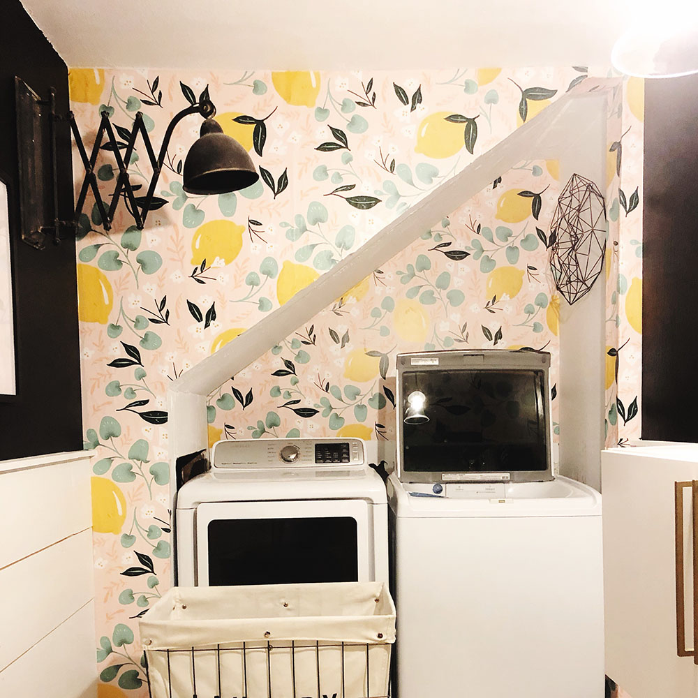 A laundry room with a colorful accent wall and white appliances.