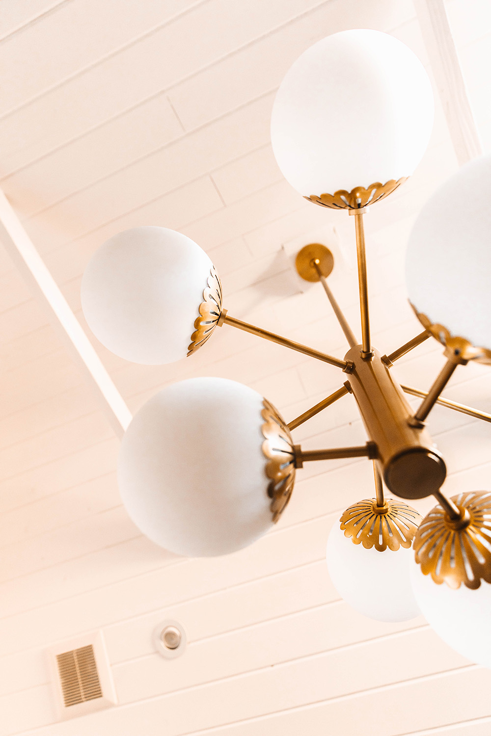 A globe lighting style chandelier hangs from a ceiling.