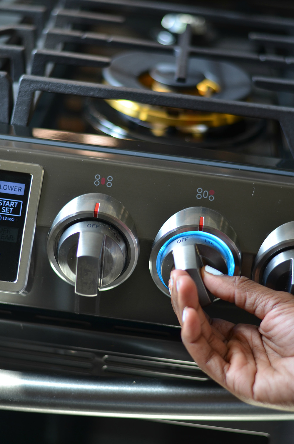 A person turning a knob on a black gas oven.