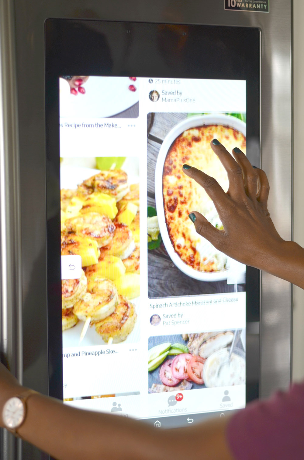 A person looking at recipes on the screen of a smart refrigerator.