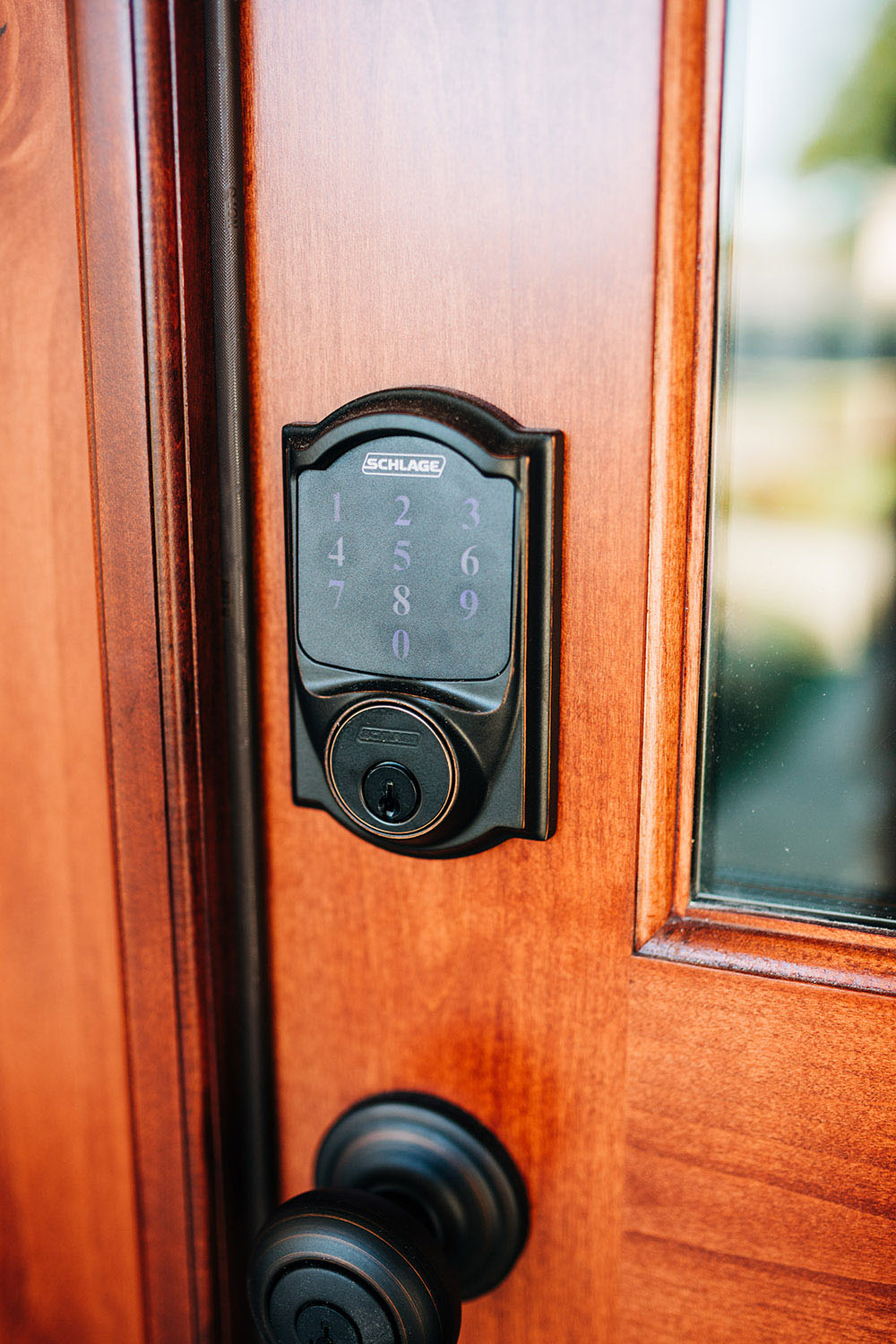 A wooden front door with a matte black smart keyless entry lock. 