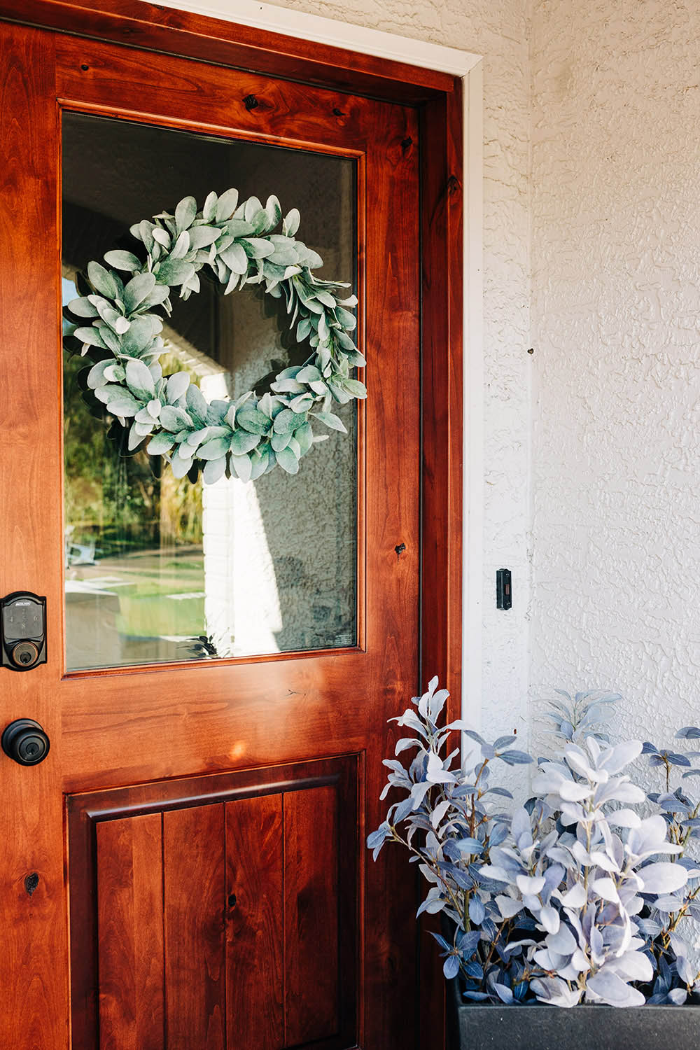 A front door decorated with a large faux green wreath.