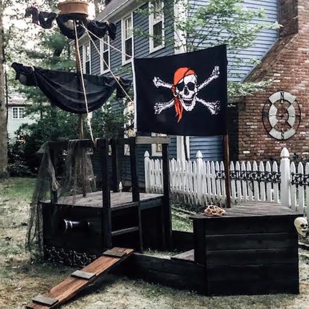 A DIY pirate ship with a flag is displayed in a front yard.