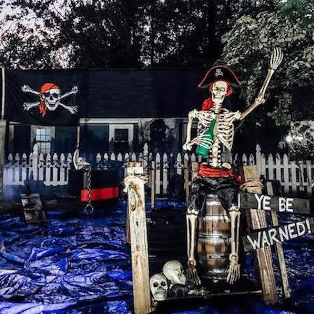 A front yard decorated with a pirate ship and skeletons.