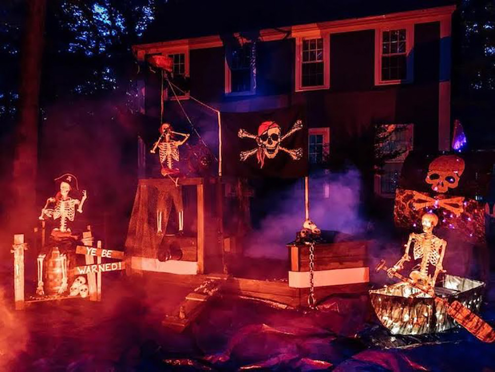 A yard decorated a night with a foggy pirate ship in orange lighting.
