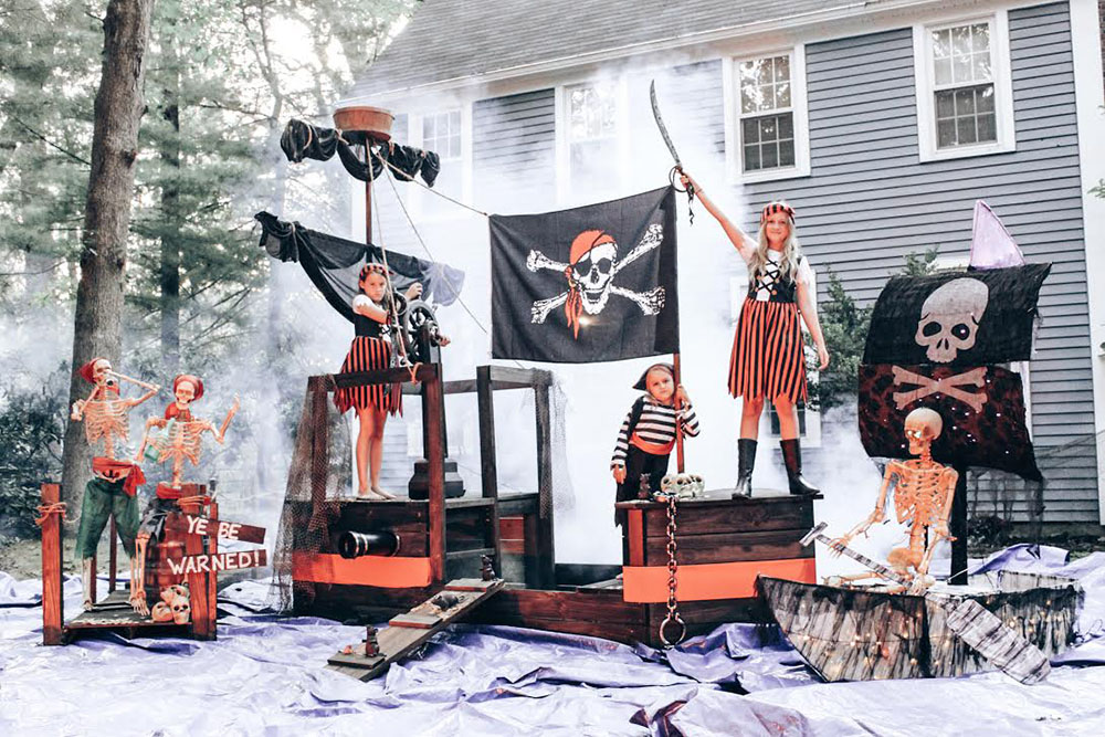 A group of children pose on a pirate ship decorated with skeleton pirates.