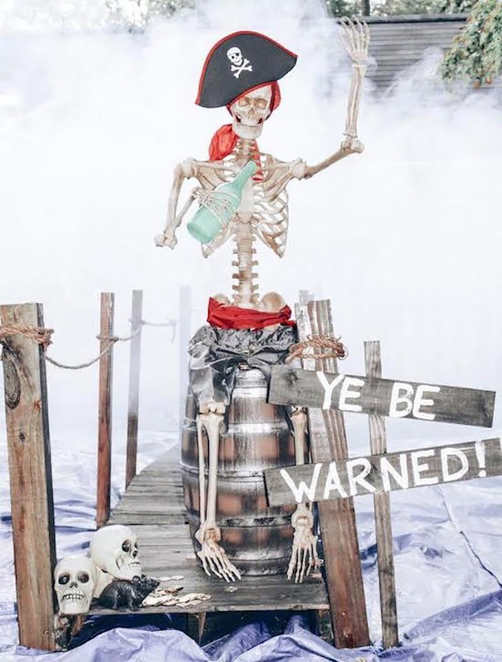 A skeleton in a pirate hat sitting on a barrel.