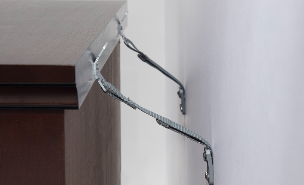 A dresser is anchored to a wall. A dresser is anchored to a wall.
