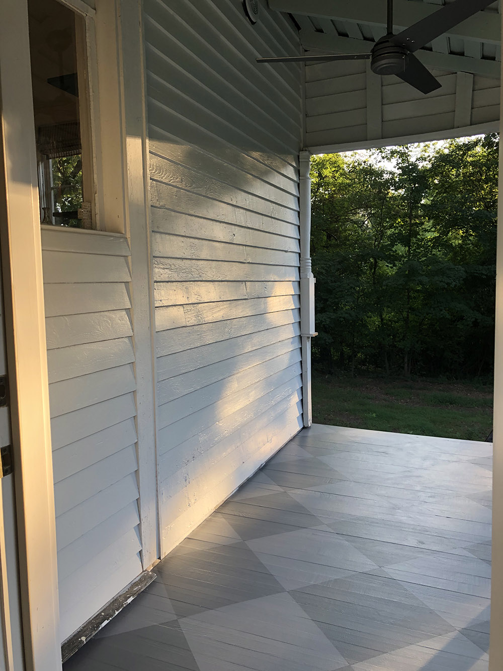A porch floor painted in a diamond pattern with two shades of gray.