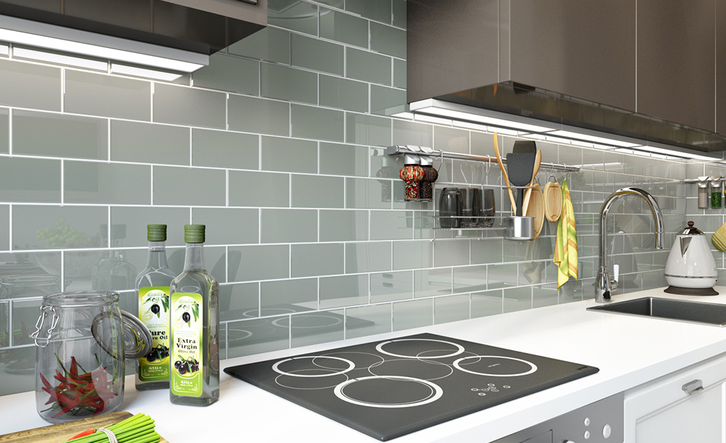 A glass backsplash in gray subway tile gives a sleek look to a modern kitchen.