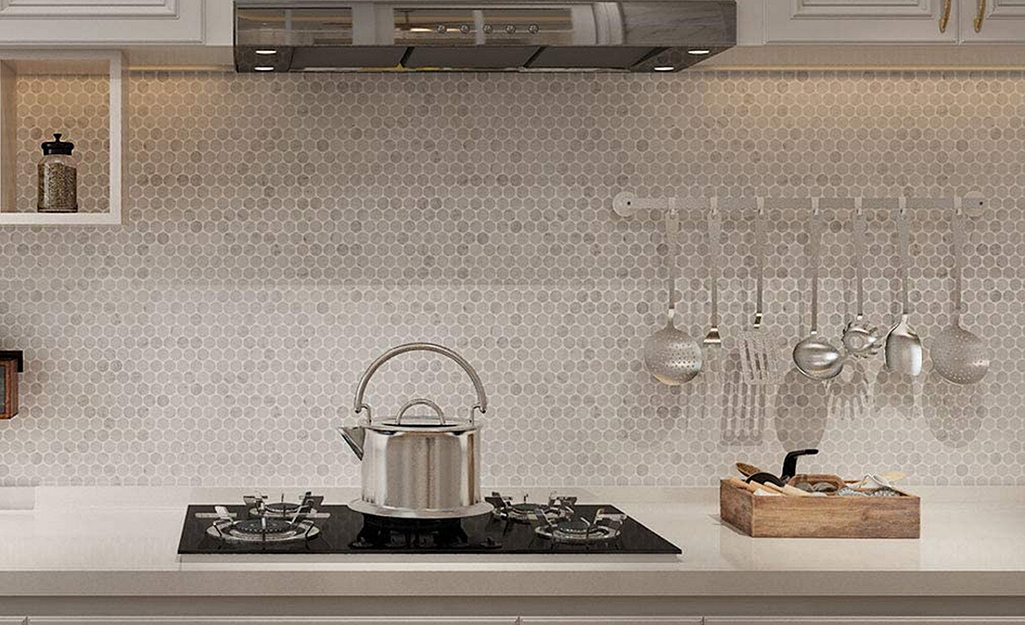 Monochromatic neutral penny tile lets hanging utensils shine as a backsplash for an industrial kitchen.