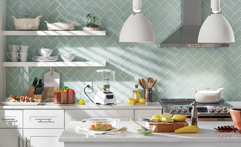 Glass herringbone tile in sea green is a classy choice as a backsplash for a French country kitchen.