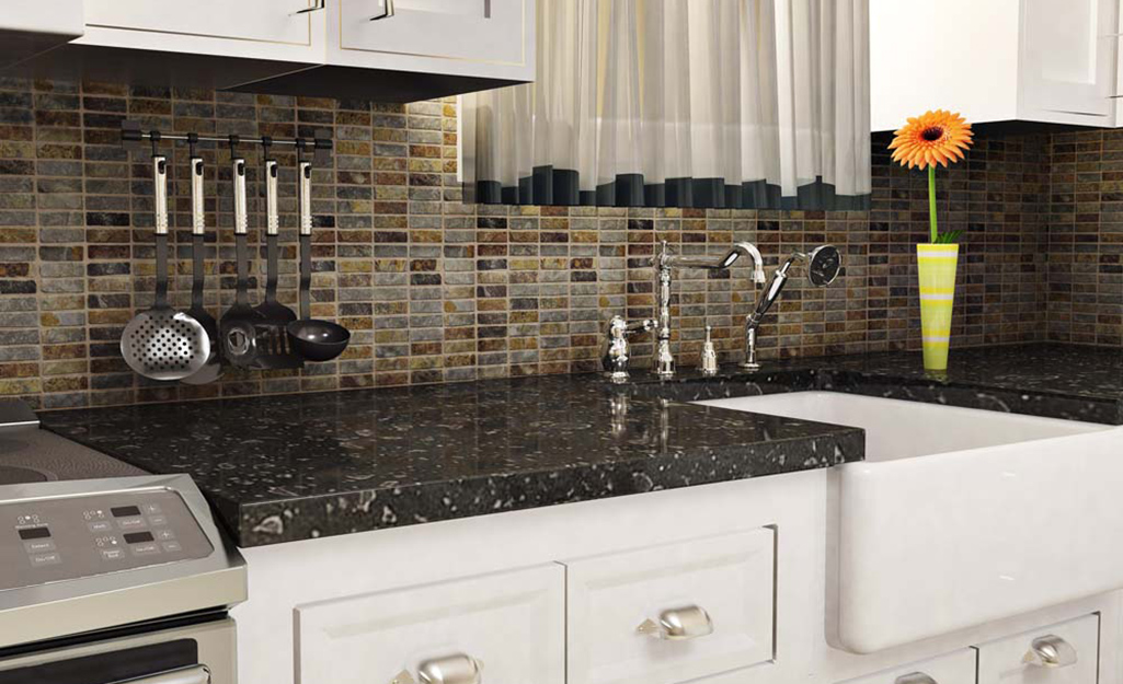 A cool brown monochromatic tile with hanging utensils saves space as a backsplash for a small kitchen.
