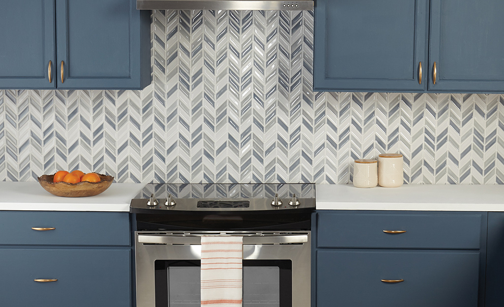 A staggered chevron tile backsplash in white and gray highlights slate blue cabinets.