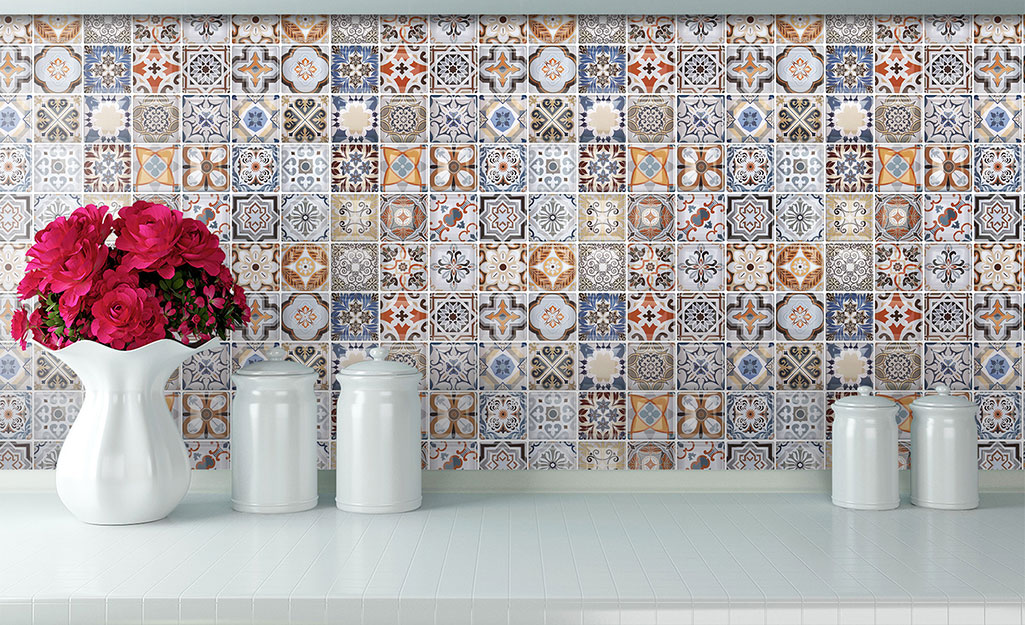 Intricately patterned small tiles make a colorful backsplash in a white kitchen.