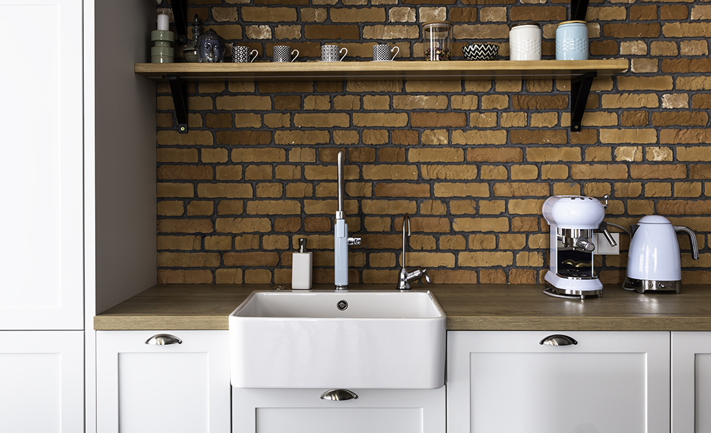 A brick backsplash provides a stunning backdrop in a farmhouse kitchen.