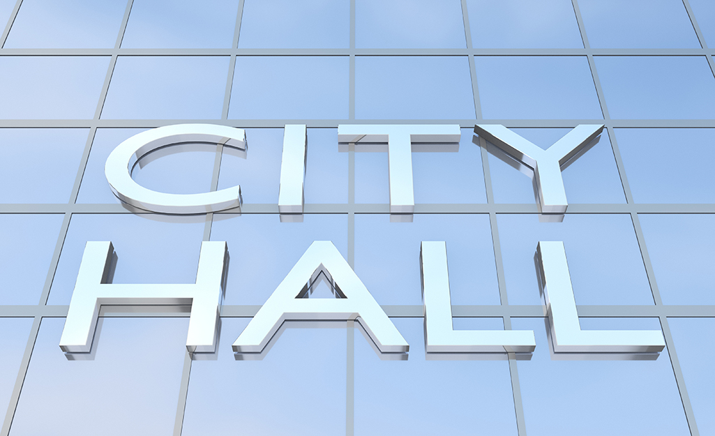 A glass building with a letters that say city hall on it. 