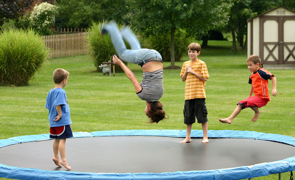 Mom and children playing on a trampoline.